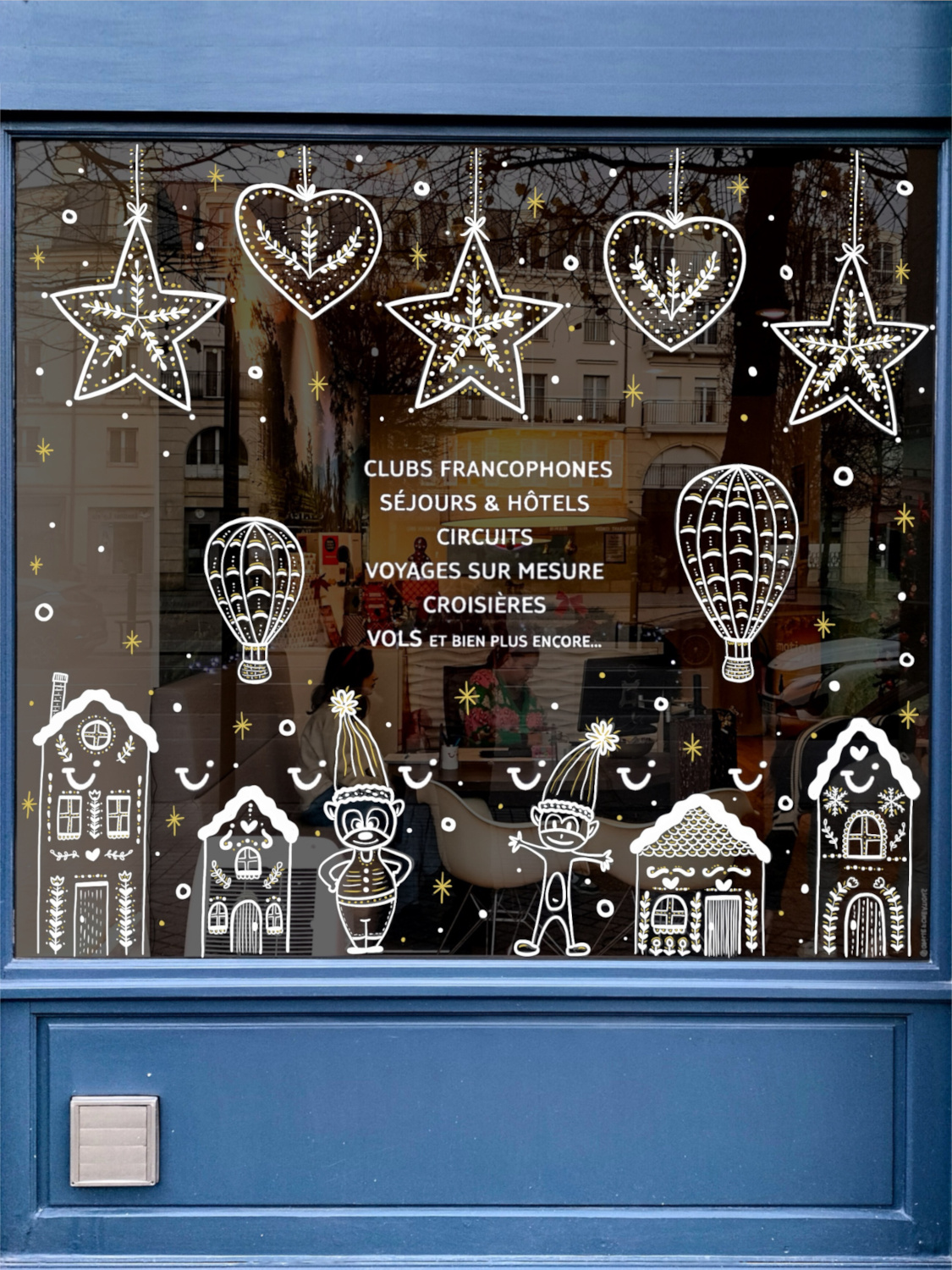 Peinture sur vitrine à Val d'Europe en Seine et Marne (77) sur le thème de Noël avec des maisons type pain d'épice, des étoiles et des montgolfières