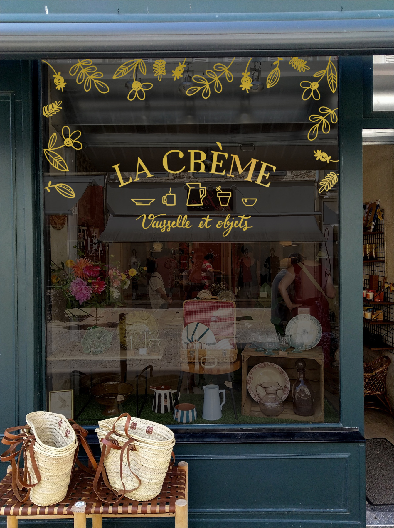Peinture sur vitrine à l'acrylique doré pour un magasin concept store d'objets vintage (décoration, vaisselle).
Le logo est repris au centre, et des décorations florales viennent agrémenter le tour de la vitrine.